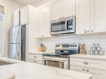 Kingston apartment for rent - a kitchen with white cabinets and a stove and a microwave