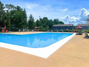 Augusta apartment for rent - a swimming pool with chairs around it and trees in the background