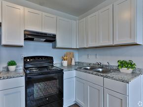 Augusta apartment for rent - a kitchen with white cabinets and black appliances and a sink