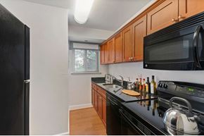 Vienna apartment for rent - A kitchen with black appliances and wooden cabinets.
