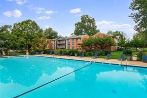 Vienna apartment for rent - A large swimming pool in front of a building surrounded by trees.