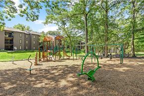 Reston apartment for rent - A playground with swings and a slide on brown sandy ground.