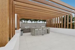 Dania Beach apartment for rent - A modern outdoor dining area with a long wooden pergola.