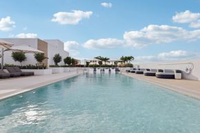 Dania Beach apartment for rent - A long rectangular pool with a white wall on one side.