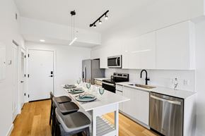Dania Beach apartment for rent - A modern kitchen with white cabinets and a stainless steel dishwasher.