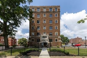 Indianapolis apartment for rent - A large brick apartment building with a black fence in front  at Marleigh apartments located in Indianapolis, IN