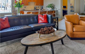 Lynnwood apartment for rent - A black couch with red pillows sits in a living room with a wooden coffee table in front of it.