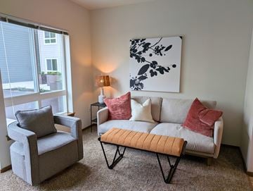 Everett apartment for rent - A living room with a grey couch, two grey armchairs, a small table with a lamp, and a large abstract painting on the wall.