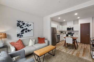 Everett apartment for rent - A modern living room with a grey couch, a wooden bench, and a painting on the wall.