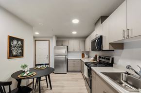 Lakewood apartment for rent - A modern kitchen Kendrick Landing, Affordable Housing in Lakewood, WA with a energy efficient appliances round table and chairs, a fridge, a microwave, and a sink.