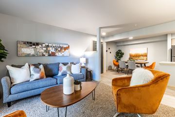 Everett apartment for rent - a living room with blue couches and chairs and a dining room table