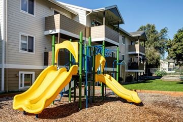 E. Wenatchee apartment for rent - A playground with a yellow slide in front of a building.