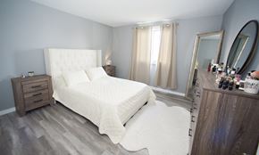 Cornwall apartment for rent - A bedroom with a large bed and a vanity with a mirror.