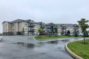 Saint John townhouse for rent - Apartment complex with a wet parking lot in front.