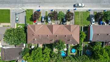 Gatineau apartment for rent - A large building with a brown roof is surrounded by trees and has a pool in front.