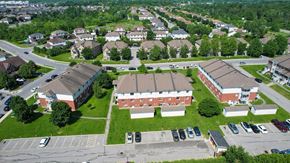 Gatineau apartment for rent - A large red brick building sits in the middle of a green grassy area.