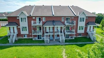 Gatineau apartment for rent - A red brick building with white railings and stairs leading to the entrance.