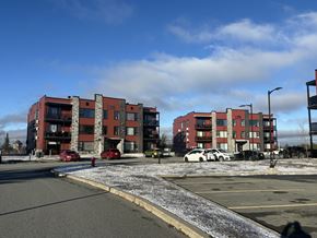 Val D'or apartment for rent - A parking lot in front of a red and grey apartment building.