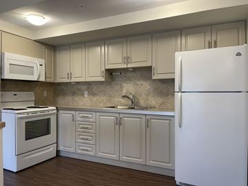 Oshawa apartment for rent - A kitchen with white appliances and cabinets.