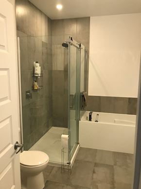 Embrun apartment for rent - A white toilet is in a bathroom with a glass shower door.
