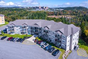 Saint John townhouse for rent - A large building with a parking lot in front of it.