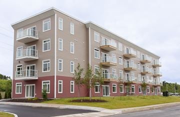Saint John townhouse for rent - A large apartment building with multiple balconies and windows.