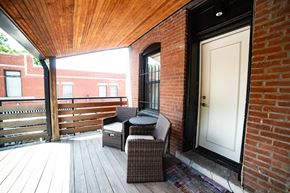 Kansa City apartment for rent - A patio with a white door and a brown wicker chair.