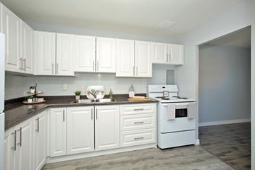 Oshawa apartment for rent - A kitchen with white cabinets and a white stove top oven.