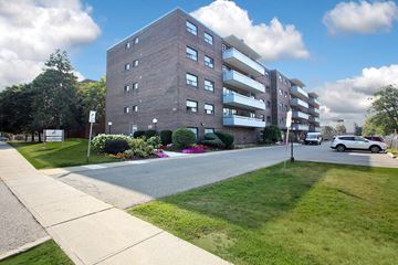 Oshawa apartment for rent - A large brick building with a green lawn in front.