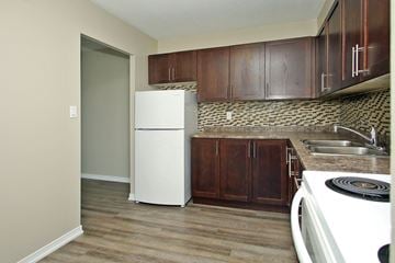 Oshawa apartment for rent - A kitchen with a white fridge and wooden cabinets.