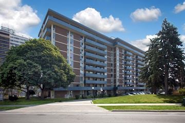 Oshawa apartment for rent - A large building with a parking lot in front.