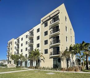 West Palm Beach apartment for rent - A tall building with balconies and palm trees in front.