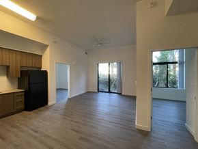 West Palm Beach apartment for rent - A spacious living room with a black refrigerator and wooden cabinets.