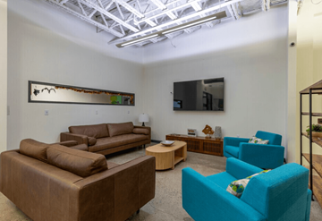 Southfield apartment for rent - A living room with a brown couch, blue chair, and a painting on the wall.