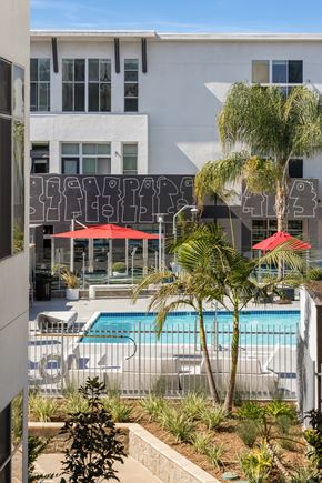 North Hollywood apartment for rent - A pool surrounded by palm trees and red umbrellas.