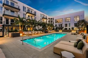 Los Angeles apartment for rent - A swimming pool surrounded by lounge chairs and palm trees.