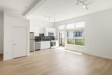 North Hollywood apartment for rent - A spacious kitchen with white cabinets and appliances, a large window, and a wooden floor.
