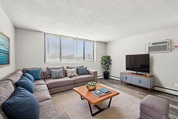 Minneapolis apartment for rent - A living room with a grey couch, a wooden coffee table, a television, and a painting on the wall.