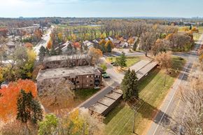 North St. Paul apartment for rent - A large building sits in the middle of a grassy area with trees in the background.