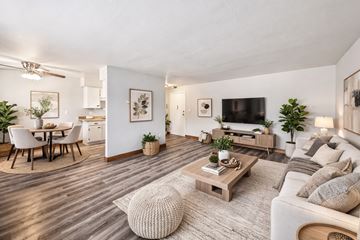 Minneapolis apartment for rent - A modern living room with a white couch, a wooden coffee table, and a dining table with chairs.