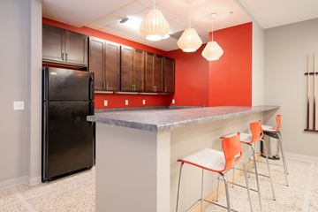 Minneapolis apartment for rent - A kitchen with a black refrigerator and orange chairs.