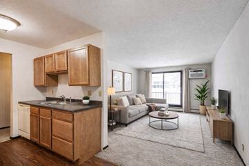 Eagan apartment for rent - A modern kitchen with wooden cabinets and a grey sofa in the living room.