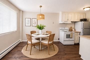 Roseville apartment for rent - A dining room with a table set for two and a kitchen area with white appliances.