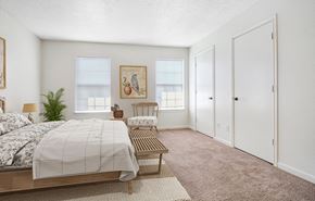Omaha townhouse for rent - a bedroom with a bed and a chair and a closet at The Bluffs at Cherry Hills, Omaha, 68122