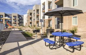 Glendale apartment for rent - A playground with a slide and a picnic table with blue benches is in front of apartment buildings.