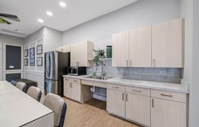 Fort Myers apartment for rent - A kitchen with a white table and chairs, a refrigerator, a sink, and cabinets.