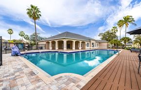 Fort Myers apartment for rent - A large outdoor swimming pool with a wooden deck and a house in the background.
