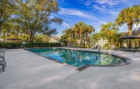 Cape Coral apartment for rent - A swimming pool surrounded by trees and a fence.