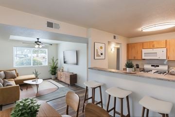 Albuquerque apartment for rent - A well-lit kitchen with a bar area and a living room with a couch and a coffee table.