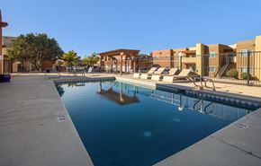 Albuquerque apartment for rent - A swimming pool in front of a building with a clear blue sky.
